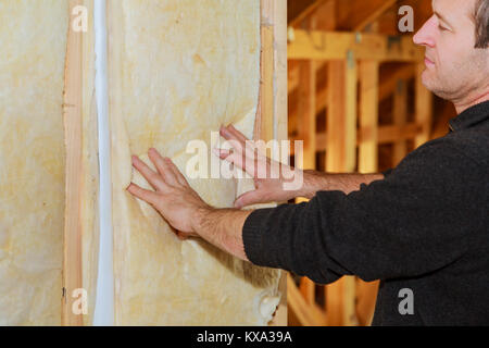 L'uomo la posa di strato di isolamento termico sotto il tetto - utilizzando la lana minerale Installazione pannelli di isolamento in casa isolamento della casa Foto Stock