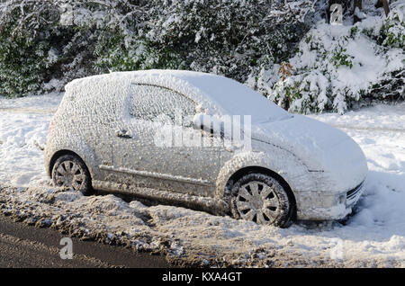 Auto abbandonate coperte di neve su una strada principale dopo la neve caduta. Foto Stock