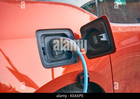 Elettrico auto parcheggiata e collegata a una stazione di carica Foto Stock