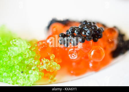 Close-up di un piccolo aiutare di nero, il rosso e il verde il caviale. Solo caviale nero è effettivo il caviale. Caviale rosso è il salmone roe, verde il caviale è un'alga. Foto Stock