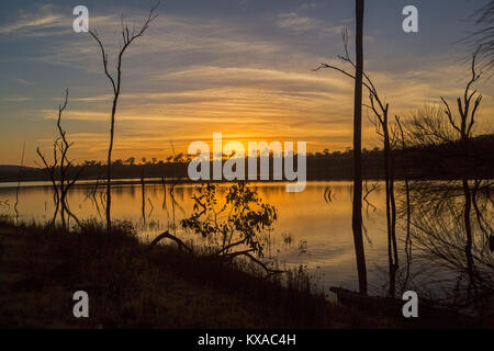 Colorato sunrise / Tramonto su acque calme del vasto lago e foresta alla pittoresca diga Paradise, vicino a Bundaberg, Queensland, Australia Foto Stock