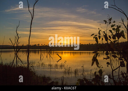 Colorato sunrise / Tramonto su acque calme del vasto lago e foresta alla pittoresca diga Paradise, vicino a Bundaberg, Queensland, Australia Foto Stock