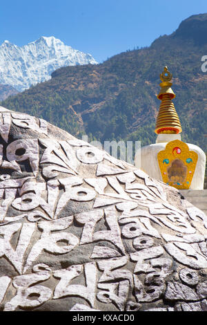 Un monumento Buddista sulla strada per il campo base Everest. Mani pareti con mantra, uno stupa e bandiere di preghiera. In serata sarete ricompensati con una deliziosa cucina nepalese attorno alla sala da pranzo fire sorseggiando un tè Sherpa e conversare con altri like-minded viaggiatori. Foto Stock