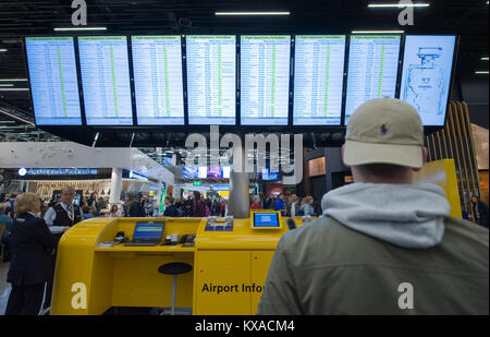 AMSTERDAM, Paesi Bassi - 27 DIC 2017: un uomo sta guardando le schermate di informazioni per controllare il suo volo sull aeroporto di Schiphol nei pressi di Amsterdam Foto Stock