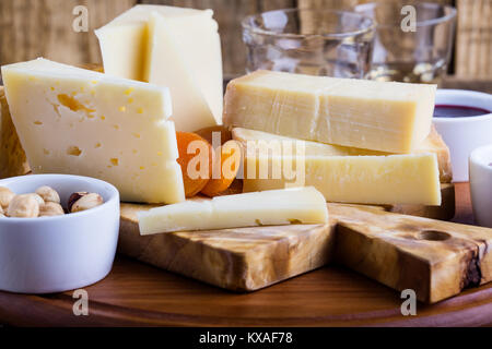 Formaggi, marmellata di frutta, noci e vino sul tagliere di legno, delizioso antipasto di vacanze Foto Stock