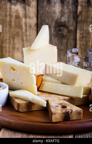Formaggi, marmellata di frutta, noci e vino sul tagliere di legno, delizioso antipasto di vacanze Foto Stock