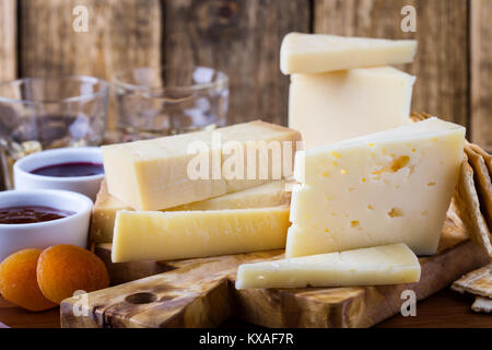 Formaggi, marmellata di frutta, noci e vino sul tagliere di legno, delizioso antipasto di vacanze Foto Stock
