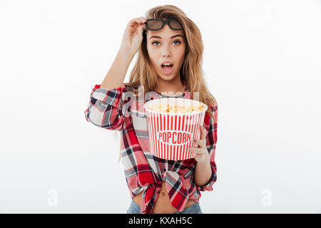 Ritratto di una bella ragazza scioccato in plaid shirt guardando film con popcorn isolate su sfondo bianco Foto Stock