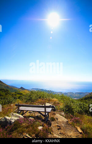 Solitario panca in legno di fronte al sole e splendenti nel Mar Mediterraneo, nella nazionale del Beigua Geopark, Liguria, Italia Foto Stock