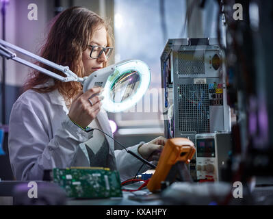 Il tecnico di laboratorio bianco ricoprire con un dispositivo di misurazione in un laboratorio di elettronica, Austria Foto Stock