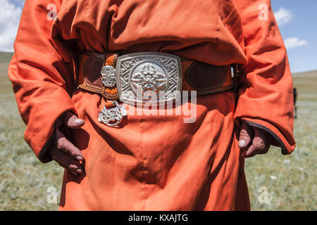 La sezione centrale del uomo mongolo indossando deel, vestito nazionale della Mongolia, legato con cintura in cuoio con grande fibbia d'argento, Naadam Festival, Bunkhan Valley, Bulgam, Mongolia Foto Stock