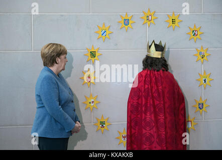 Berlino, Germania. 8 Gen, 2018. Il cancelliere tedesco Angela Merkel del cristiano Unione Democratica osserva come una ragazza del comune di San Martinus Holzheim Vescovato (Colonia) scrive una benedizione durante la tradizionale accoglienza del carol cantanti a Berlino, Germania, 8 gennaio 2018. Più di 100 carol cantanti provenienti da tutte le 27 diocesi tedesche sono stati accolti nella Cancelleria tedesca. Credito: Soeren Stache/dpa/Alamy Live News Foto Stock