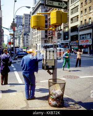New York 1980s, 5th Avenue e East 31st Street crossing, uomo con cappello appoggiato contro un'asta di senso unico, Manhattan, New York City, NY, NYC, STATI UNITI, Foto Stock