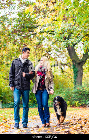 Uomo e donna con cane avente Passeggiata d'autunno Foto Stock