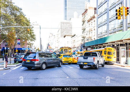 La città di New York, Stati Uniti d'America - 27 Ottobre 2017: molte automobili, giallo taxi, scuolabus, girando in semaforo con alberi d'autunno, marciapiede, costruzione, Foto Stock