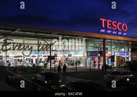 Negozio Tesco durante la notte con le luci accese e illuminato Tesco segno in un supermercato Tesco nel Regno Unito. Foto Stock