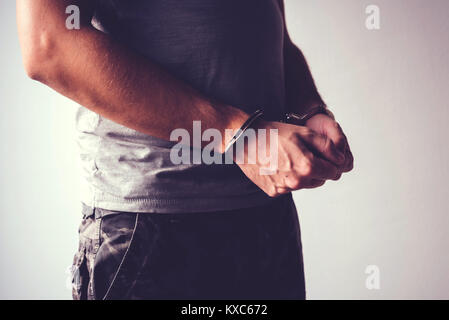 Ammanettato soldato in militari esercito vestiti. Prigioniero di guerra o arrestato terrorista, close up di mani in manette, il fuoco selettivo. Foto Stock