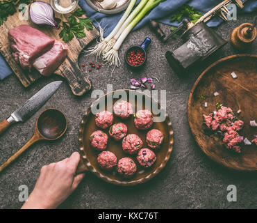 Femmina di mano azienda padella con polpettine di carne sul tavolo di cucina con ingredienti e strumenti, vista dall'alto Foto Stock