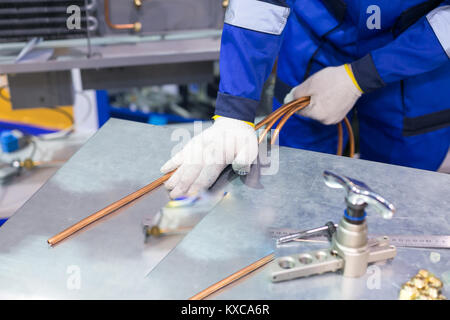 Produzione, tecnologia, concetto di fabbrica. non c'è uomo che vestito in speciale blu uniforme e guanti di protezione quando si lavora con la saldatura Foto Stock