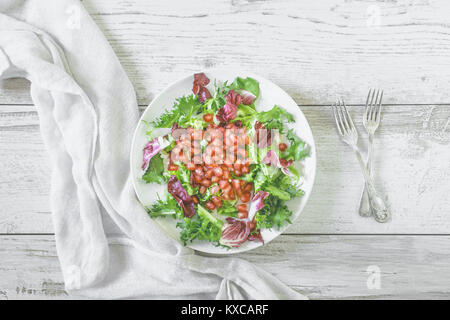 Sana insalata vegetariana con indivia, lattughe miste, rucola e melograno su bianco tavola di legno Foto Stock