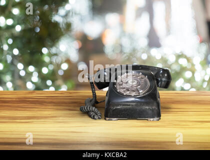 Vecchio nero telefono vintage in legno marrone tabella con notte sfondo bokeh di fondo Foto Stock