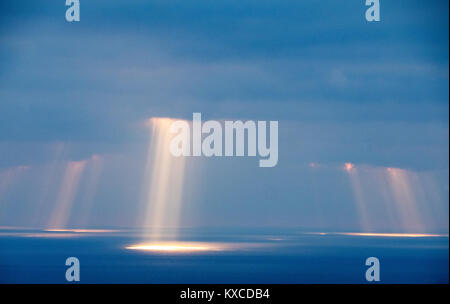 Alberi di rompere la luce del sole attraverso le nuvole sopra Coral Bay, vicino a Paphos, Cipro. Foto Stock