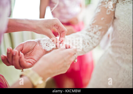 Bella bridesmaids legatura di nodi su sposa bracciali della prima del suo matrimonio cerimonia. Foto Stock