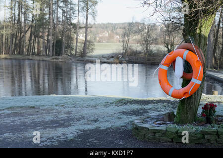 La vita di sicurezza anello arancione boa in acque profonde privato lago pesca nel paesaggio rurale Foto Stock