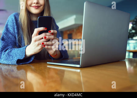 Close up le mani delle donne tenendo il telefono cellulare con la copia in bianco ghiaione dello spazio per la vostra pubblicità messaggio di testo o il contenuto promozionale, hipster ragazza guarda i video sul telefono cellulare durante la pausa caffè. Tonica. Messa a fuoco selettiva. Foto Stock