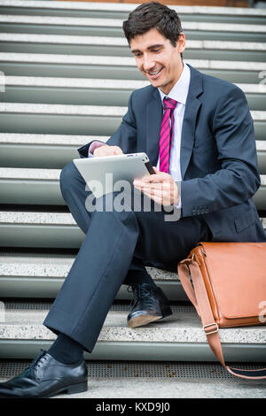 Imprenditore utilizzando una pastiglia per la comunicazione o di archiviazione dei dati fuori Foto Stock