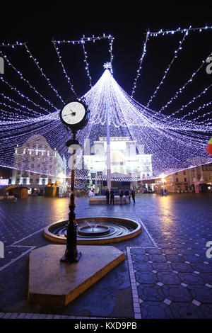 Timisoara, Romania - uno stile retrò di un orologio con una decorazione tenda di illuminazione e la casa dell'opera in background Foto Stock