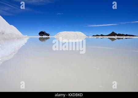 Veicolo fuoristrada si riflette in una vernice di sale, sale mining sul lago di sale, Salar de Uyuni, Uyuni, Potosi, Bolivia Foto Stock