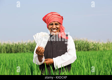 1 L'agricoltore rurale Man Standing Campo che mostra la valuta indiana note Foto Stock