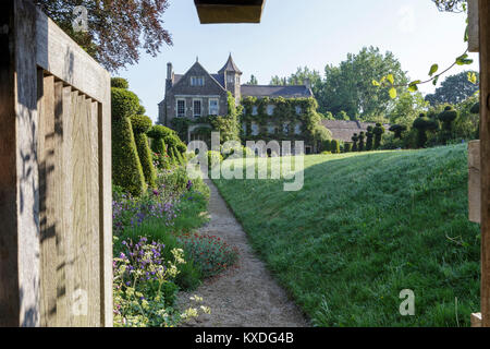 Hanham giardini di corte, Bristol. Inizio estate giardino, vista attraverso il gateway informale lungo lungo confine Foto Stock