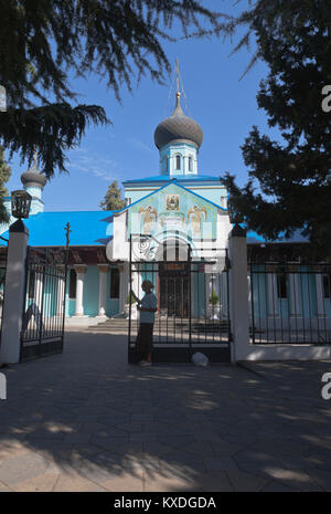 Adler, Regione Krasnodar, Russia - Luglio 7, 2016: donna anziana mendica l elemosina alle porte della chiesa della Santa Trinità in un insediamento resort Adler, S Foto Stock