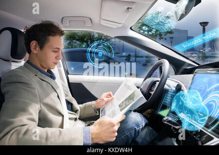 Driver caucasica rivista di lettura in auto autonoma. Auto durante la guida del veicolo. Driverless car. Foto Stock