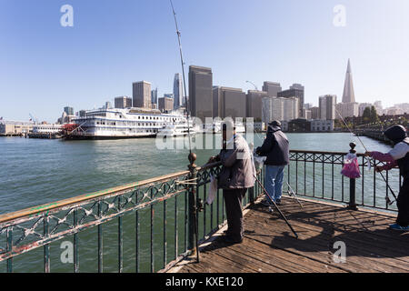 San Francisco, Stati Uniti d'America - 2 Luglio 2017: persone di pesca su un molo all'Embarcadero nel centro cittadino di San Francisco con il quartiere finanziario e il centro storico Foto Stock