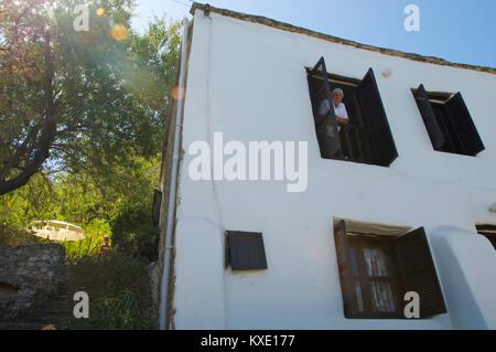 Gli stranieri locale guardando fuori della loro casa bianca che viene scavata nella montagna in Karmi, Cipro Foto Stock