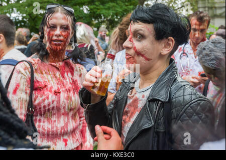 Uno zombie ha un drink in Embankment Gardens sul mondo zombie giorno carità strisciare in Londra in aiuto di St Mungo Broadway della carità sostenendo i senzatetto. Foto Stock