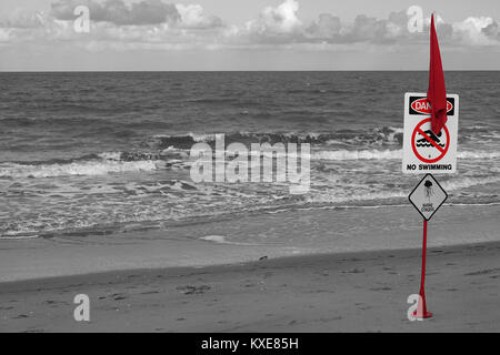 Red Flag di avviso sulla spiaggia con pericolo nessun segno di nuoto e meduse immagine colorata. pennone contro tropicale paesaggio costiera Foto Stock