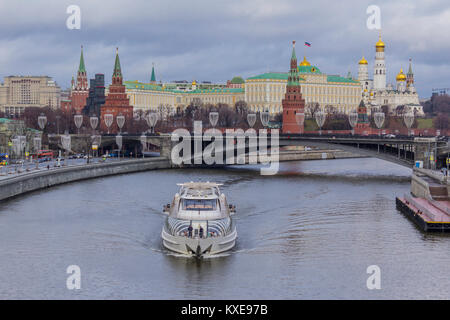 Vista del Cremlino dal ponte patriarcale. Un disgelo a metà inverno. Una gita sulla nave non congelati fiume Moskva in primo piano. Foto Stock