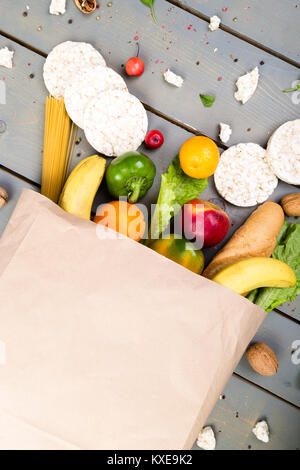 La spesa del concetto. Diversi di cibo nel sacchetto di carta su sfondo di legno. Lay piatto Foto Stock