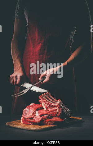 Butcher Affilare coltello per tagliare la carne cruda sul tagliere di legno Foto Stock