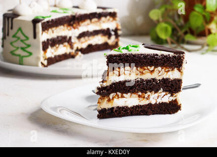 Un taglio di un nuovo anno la torta al cioccolato, una fetta su una piastra su uno sfondo luminoso Foto Stock