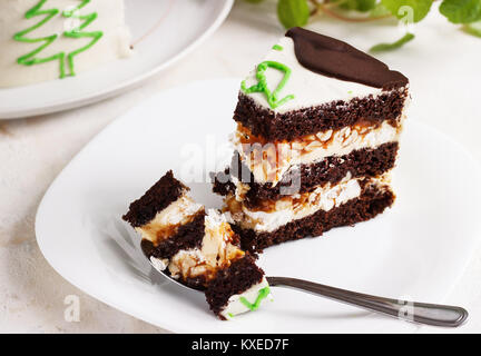 Un taglio di un nuovo anno la torta al cioccolato, una fetta su una piastra su uno sfondo luminoso Foto Stock