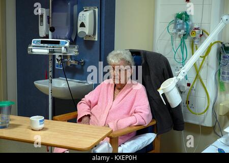 Vecchia età pensionato donna seduta in un ospedale di NHS lato ward England Regno Unito Foto Stock
