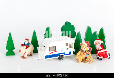 Mini figure, alberi e un giocattolo caravan in bianco. Decorazione di Natale isolato su sfondo bianco. Primo piano. Primo piano. Foto Stock