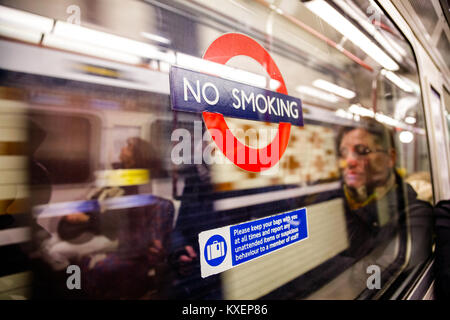 LONDON, Regno Unito - 03 novembre 2012: i passeggeri che riflette in una metropolitana di Londra trasporto finestra con nessun segno di fumare su di esso Foto Stock