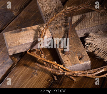 La corona di spine e chiodi con croce sulla superficie di legno Foto Stock