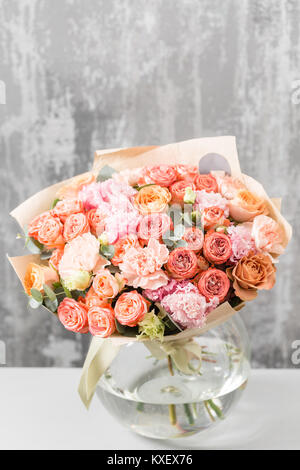 Bouquet di fiori misti in un vaso sul tavolo in legno. Il lavoro del fioraio presso un negozio di fiori Foto Stock